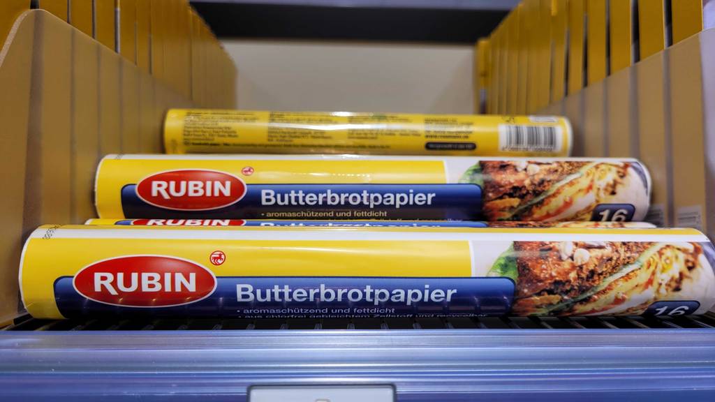Mehrere Packungen getesteter Butterbrotpapier liegen in einem Regal.