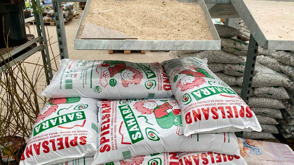 Spielsand im Test: mehrere Packungen Spielsand und darüber ein Behälter mit dem entsprechenden Sand darin.