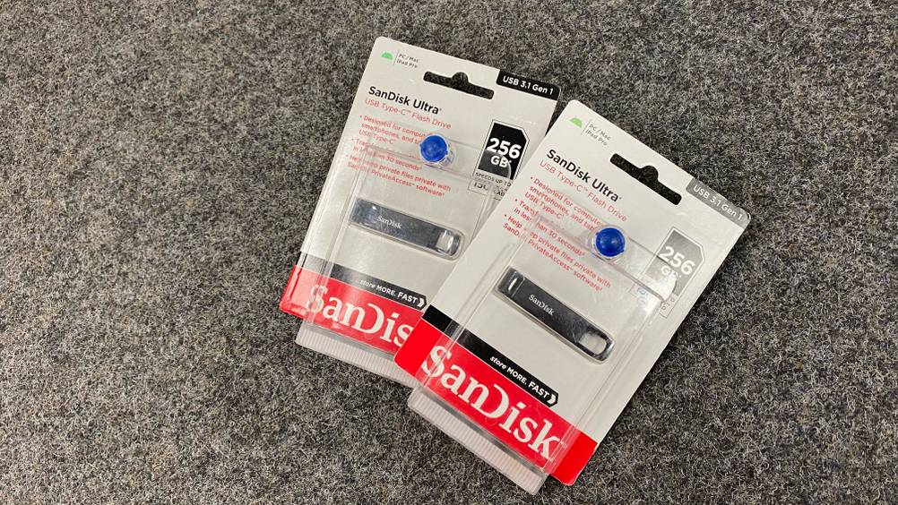 USB-Stick (256 GB) getestet: Zwei Packungen liegen leicht übereinander auf einem dunklen Teppich.