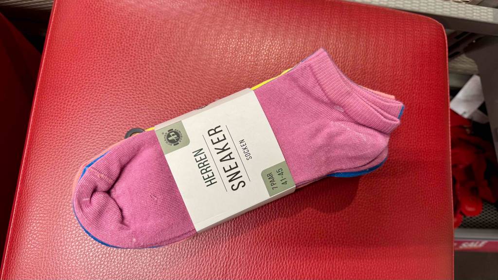 Bunte-Socken-Test: Socken in verschiedenen Farben, wobei die rosa Socken im Vordergrund sind, liegen auf einem roten Hocker.