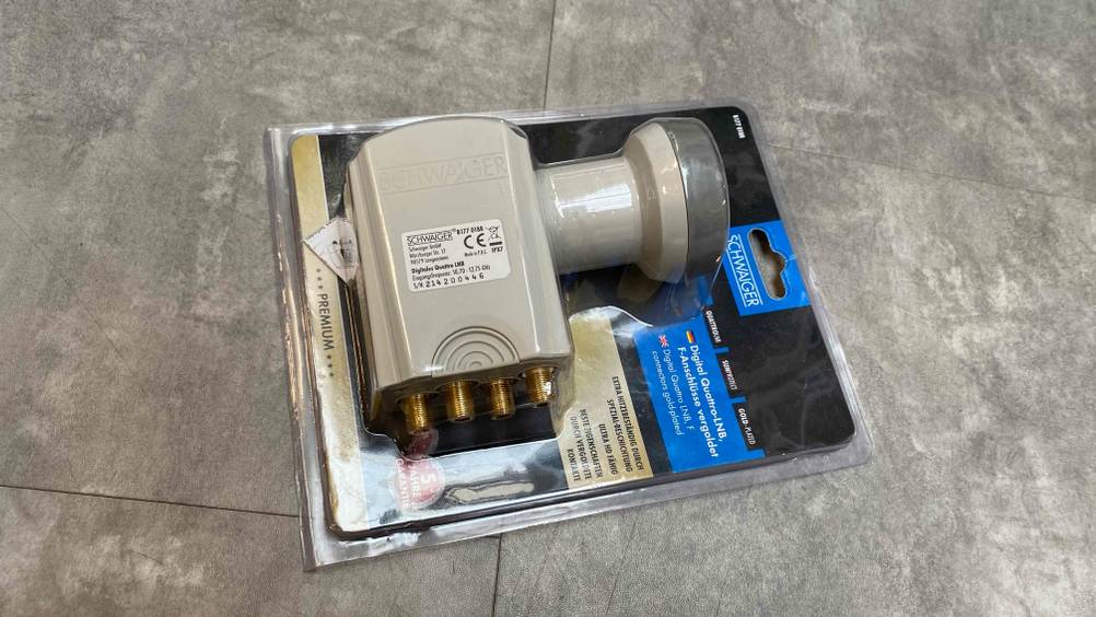 Auf einer grauen Fließenfläche liegt ein getesteter Quattro-LNB verpackt.