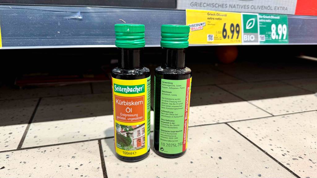Die Vorder- und Rückseite des getesteten Bio-Kürbiskernöls, die vor einem Regal stehen.