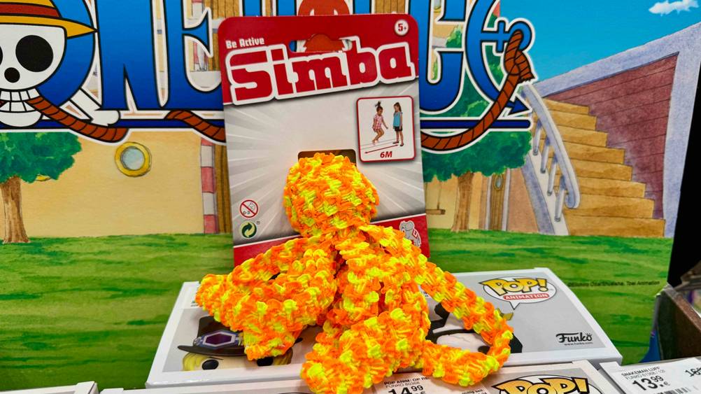 Der getestete Gummitwist in der Farbe Orange und Gelb liegt vor einem Aufsteller.