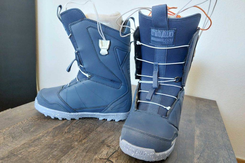 Snowboard-Boots getestet: Boots stehen auf einem Holztisch, ein Boot steht seitlich einer nach vorne