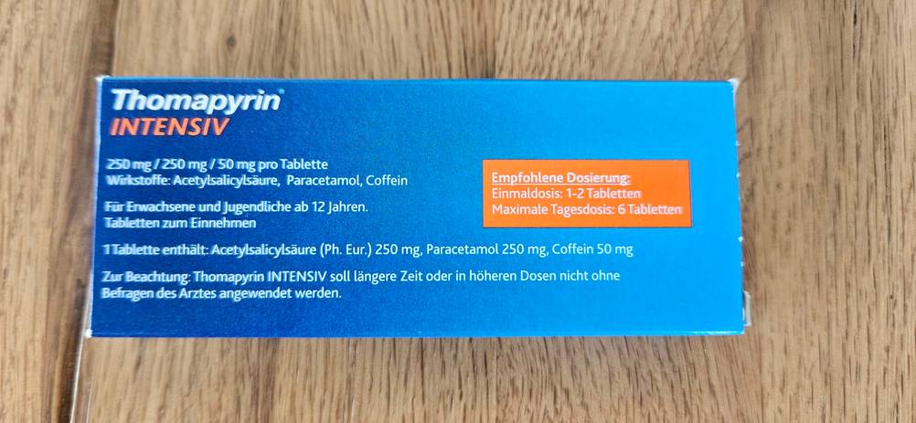 Rückseite eine Packung getestete Migräne-Tabletten auf einer Holzfläche.