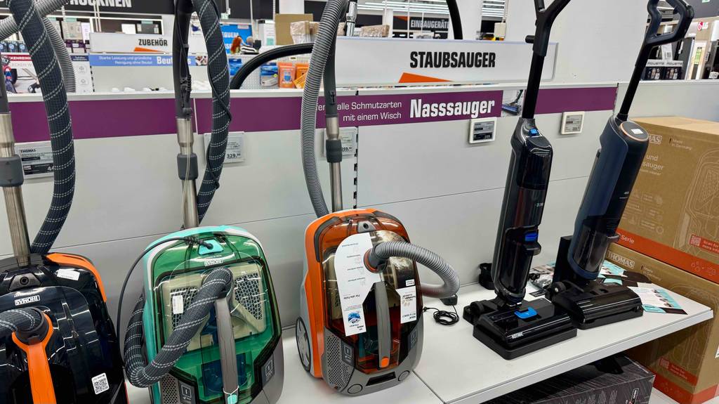 Der getestete Thomas-Staubsauger in Weiß-orange steht inklusive Zubehör neben anderen Staubsaugern im Geschäft.