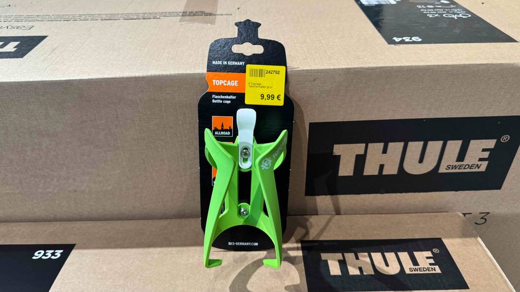 Der grüne Fahrrad-Flaschenhalter im Test steht auf einem Karton.