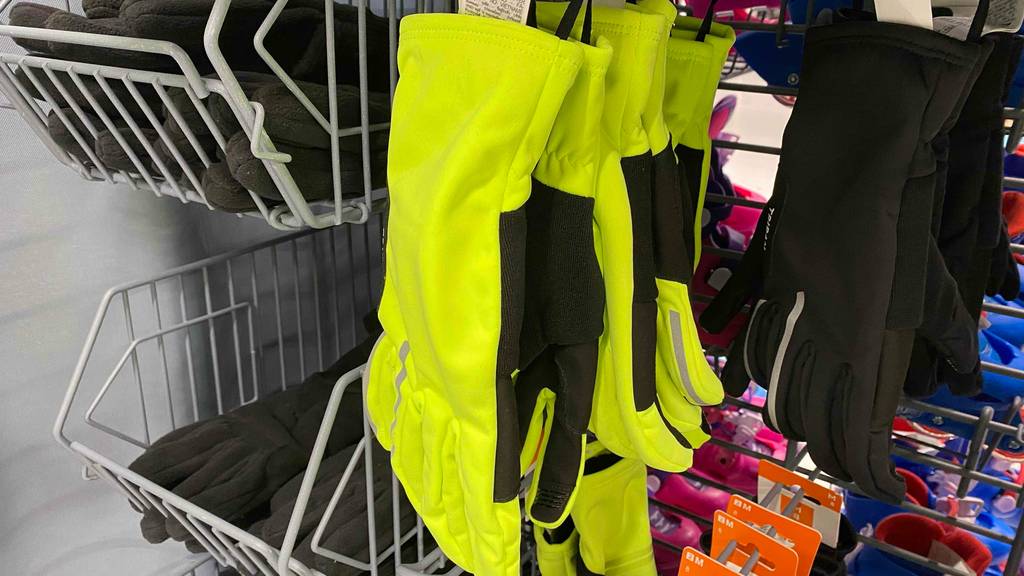 Fahrradhandschuh für den Winter getestet: Neon-gelbe Fahrradhandschuhe in einem Regal hängend neben schwarzen Handschuhen.