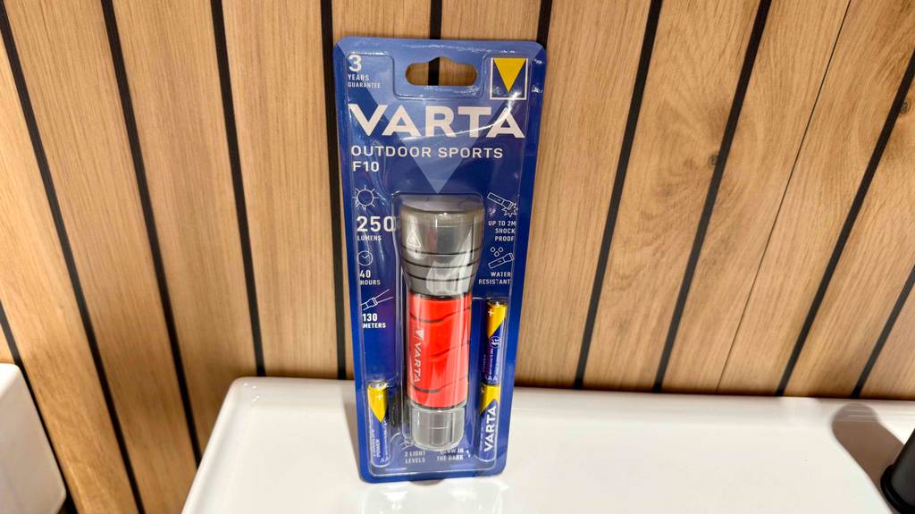 Varta-Taschenlampen im Test: Ein Modell mit rotem Handgriff steht innerhalb der Verpackung vor einer Holzwand.