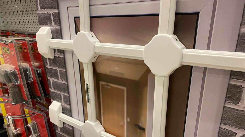 Fenstergitter-Test: Verstrebungen eines weißen Fenstergitters im Fokus.