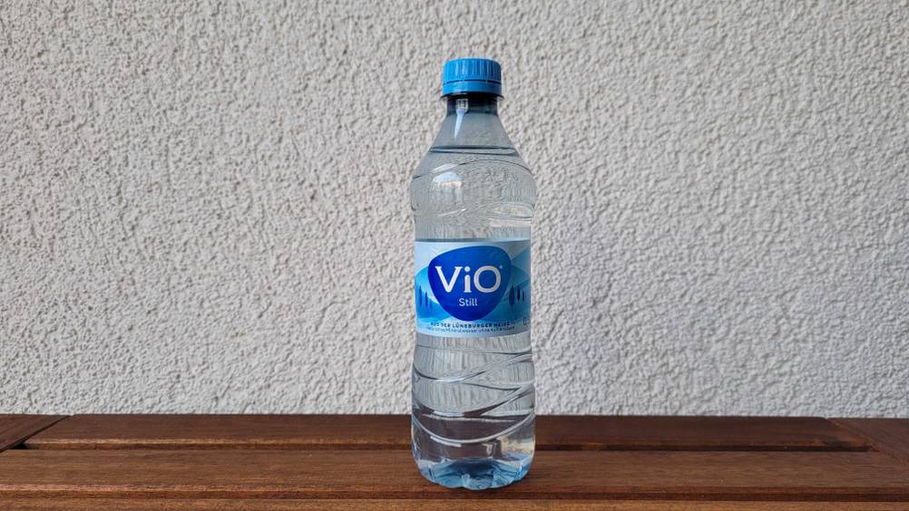 Stilles-Mineralwasser-Test: verschlossene Flasche Mineralwasser von VIO auf einem Holztisch stehend.