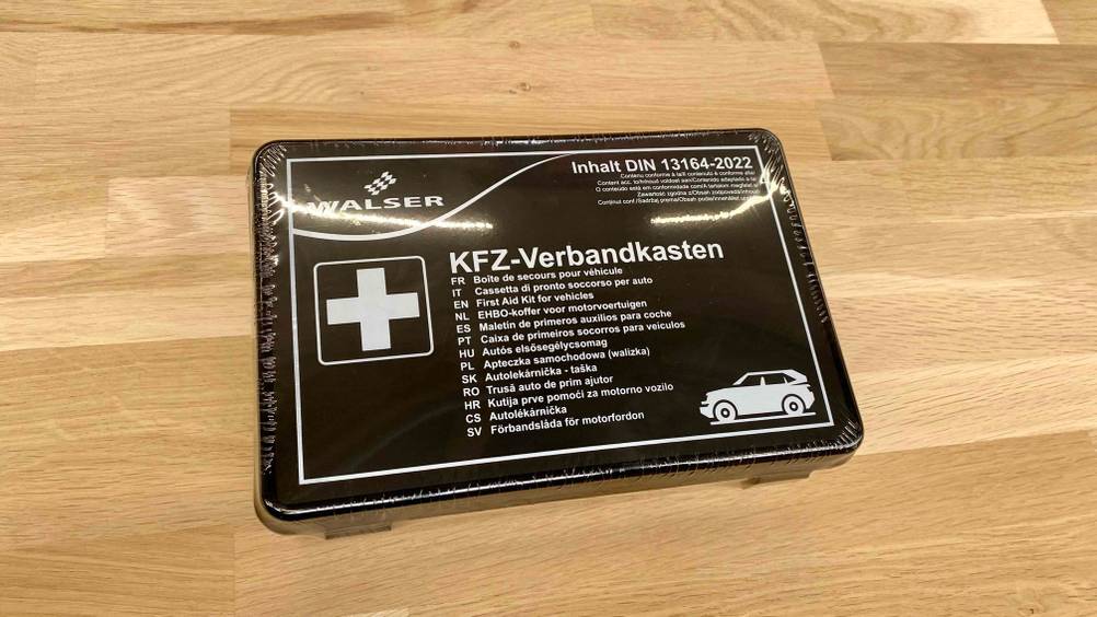 Auf einem Holzboden liegt ein getesteter Verbandskasten.