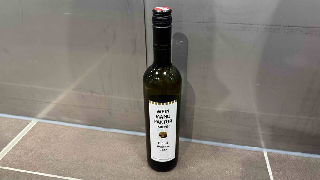 Eine Flasche getesteter grüner Veltliner steht vor einer Wand.