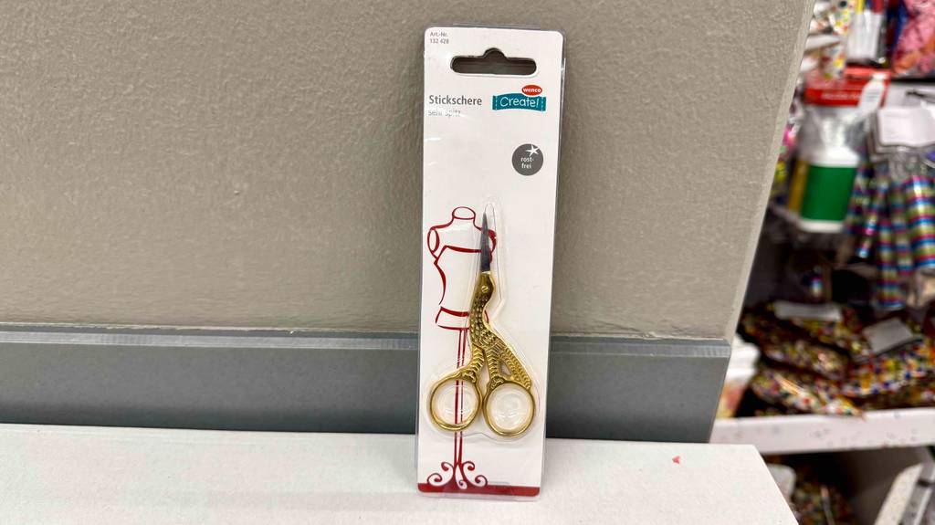 Getestete Stickschere in der Farbe Gold ist an einer Wand angelehnt.
