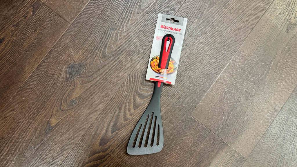 Test- Pfannenwender: Ein schwarzer Pfannenwender liegt in der Verpackung auf einem Boden.