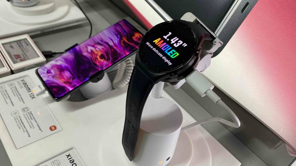Neben einem Handy auf einem Ständer befindet sich eine getestete Herren-Smartwatch für Android.