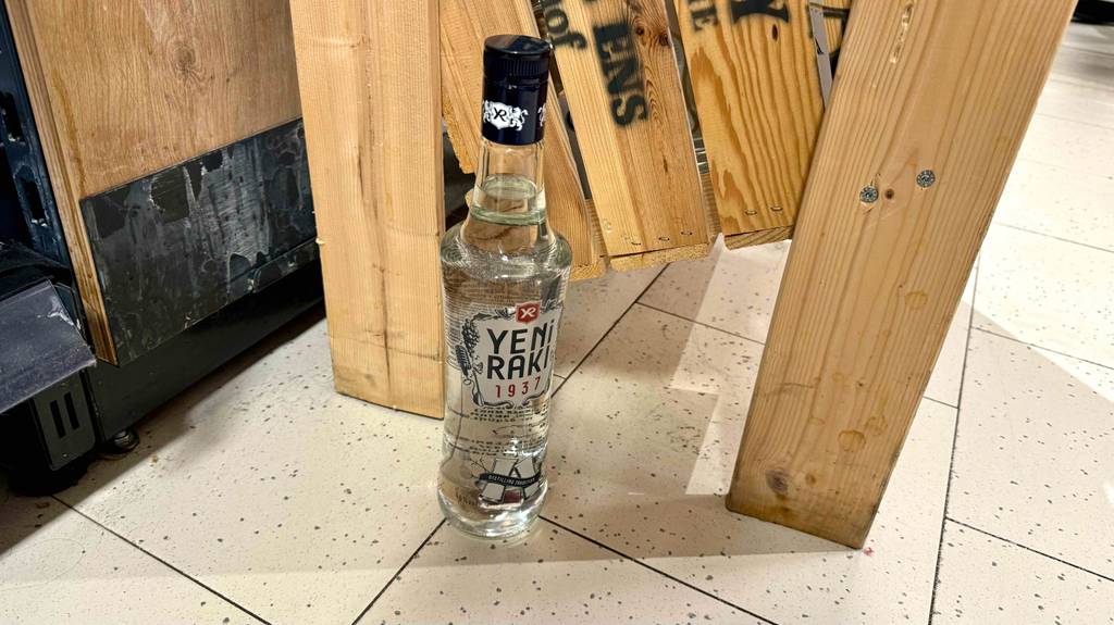Der getestete Raki steht vor Holzkisten.