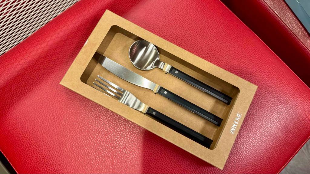 Das getestete Besteckset bestehend aus Löffel, Gabel und Messer liegt auf einer roten Sitzfläche.