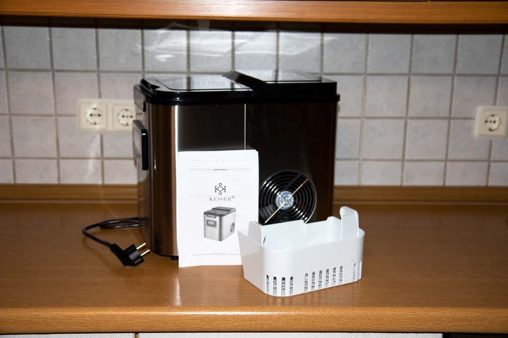 Ein Handbuch, Eisfach und eine schwarze Kesser Eiswürfelmaschine stehen auf einer Küchenzeile.