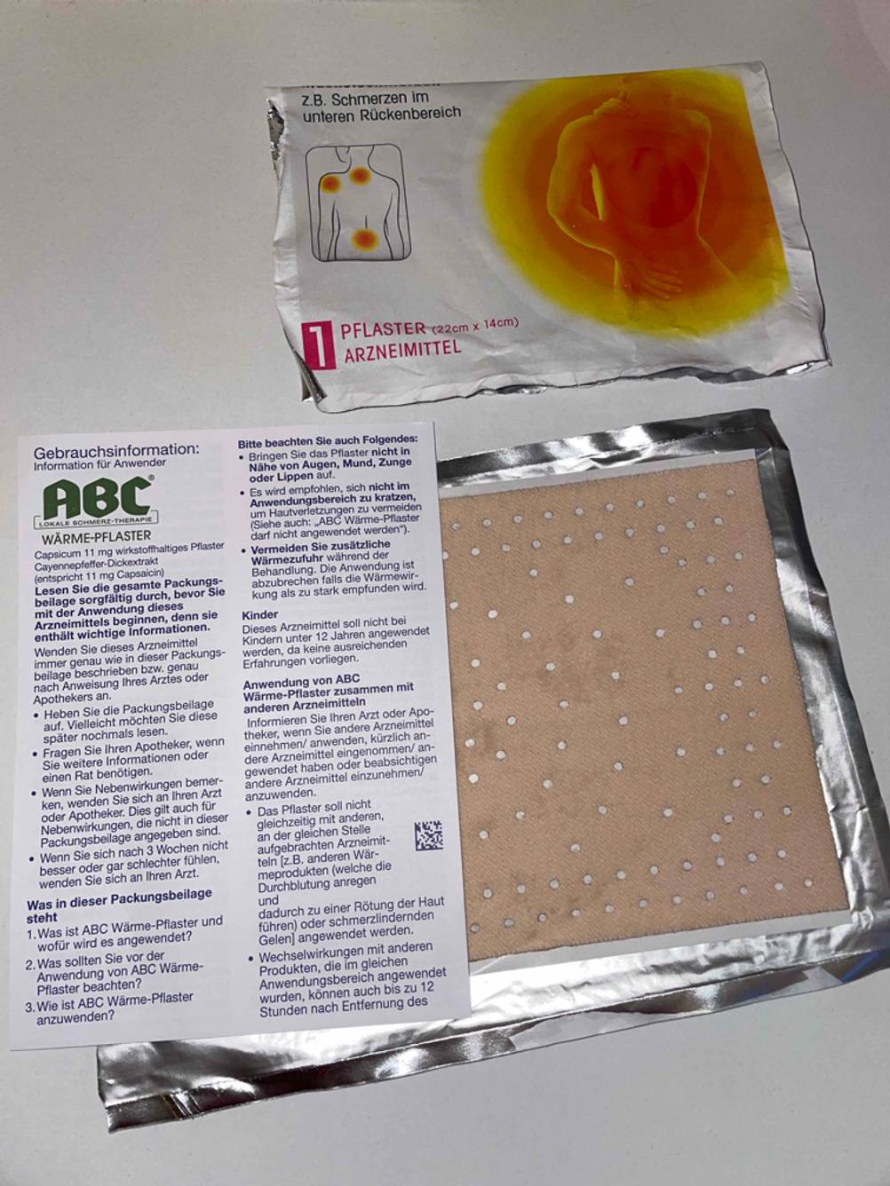 Wärmepflaster im Test: ein ausgepacktes Wärmepflaster neben der Packungsbeilage und der Folienverpackung liegend.