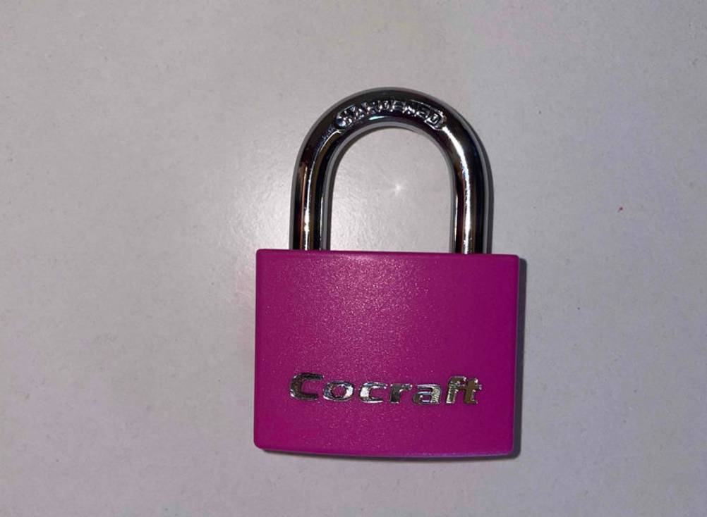 Vorhängeschloss getestet. Ein pinkes Vorhängeschloss von vorn ersichtlich liegt im geschlossenen Zustand auf einer weißen Fläche.