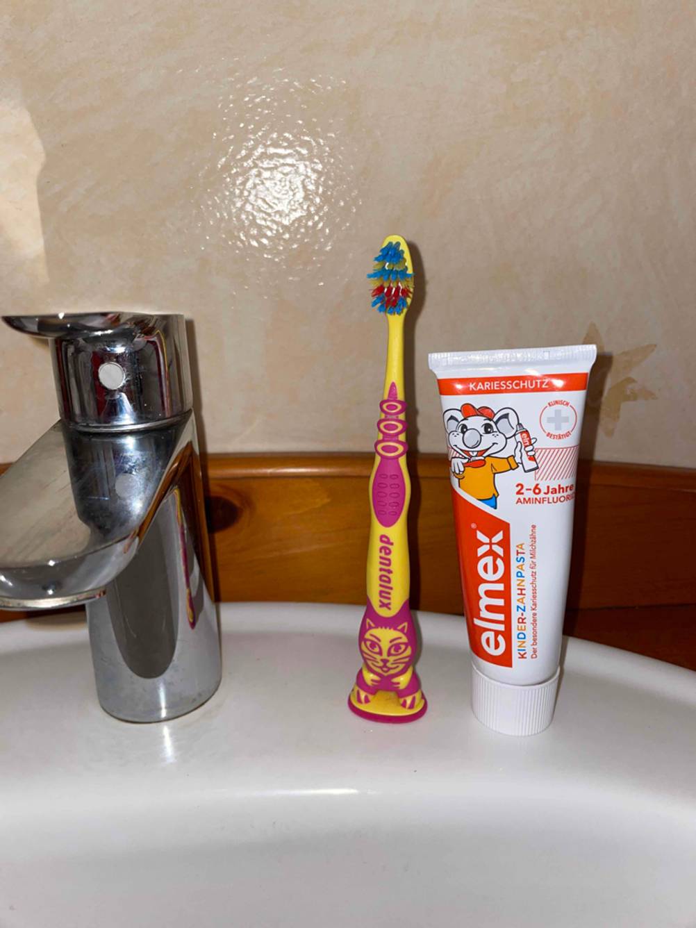 Zahnbürste und Zahnpasta auf Waschbecken.