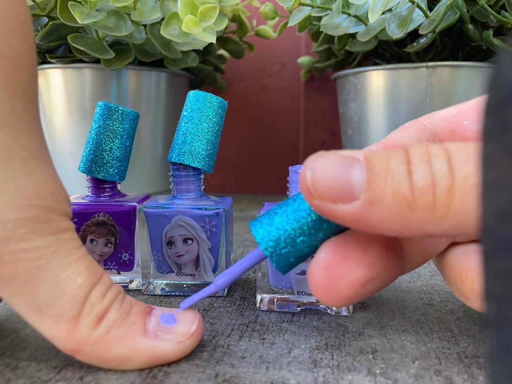Nagellack wird auf Finger aufgetragen.