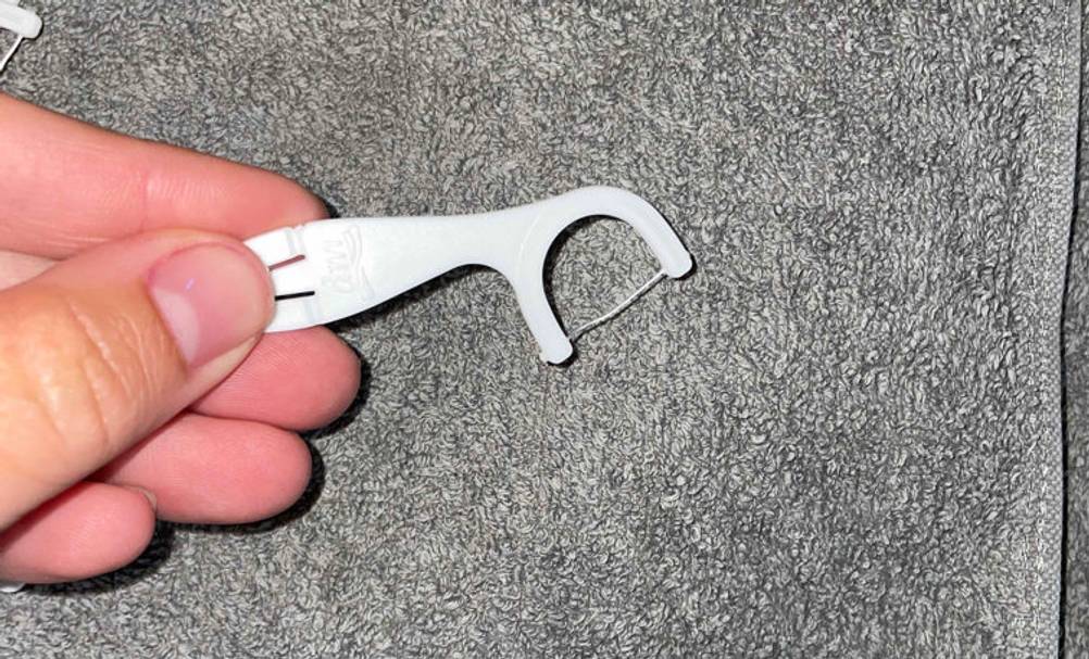 Zahnseide getestet: eine Zahnseide wird über ein graues Handtuch gehalten.
