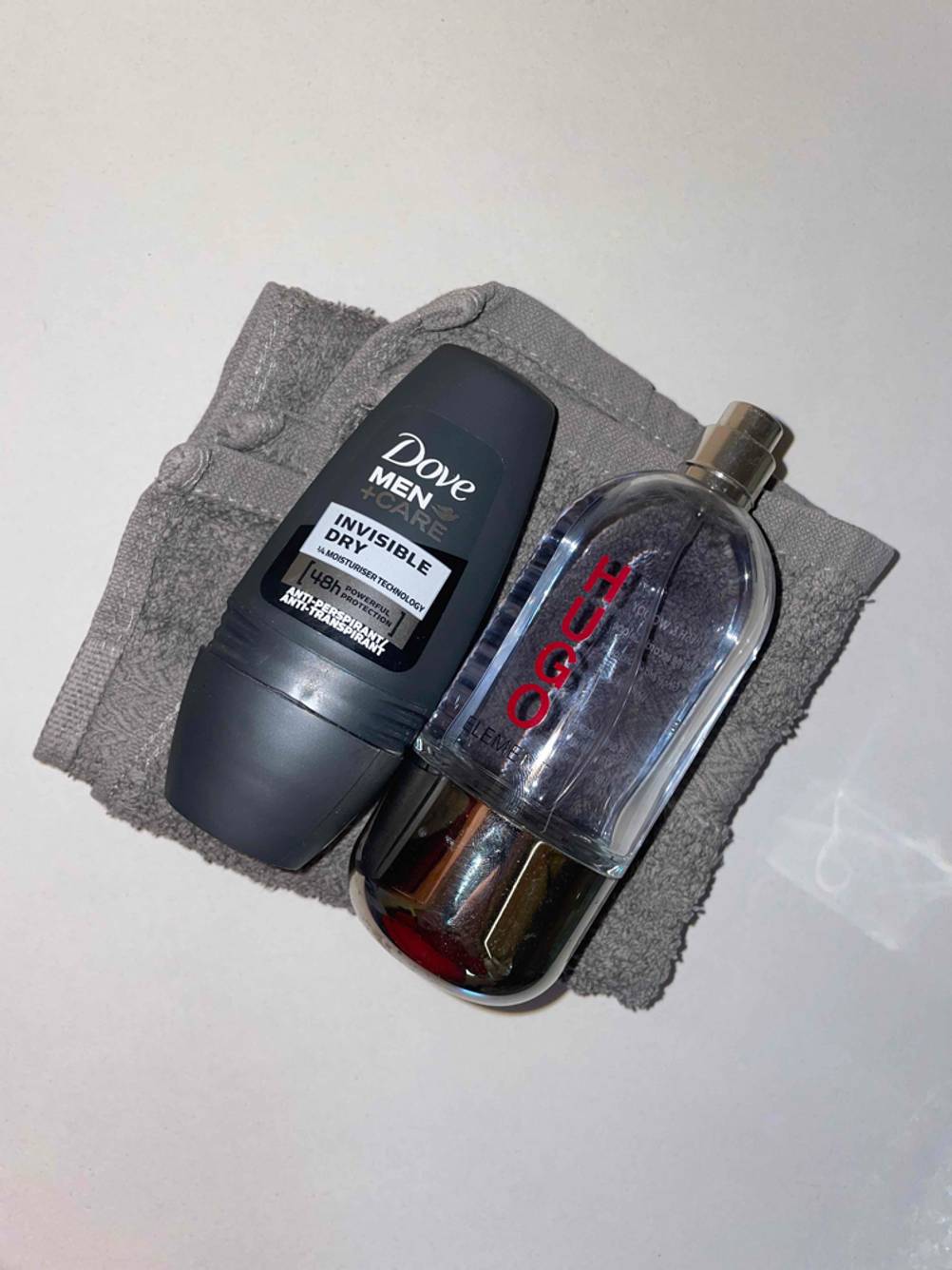 Deo-Roller und Parfum auf einem Handtuch.