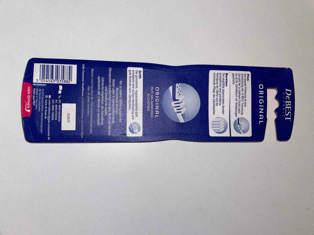 Zahnbürste-Test: Verpackungsrückseite einer Zahnbürste liegend auf einer weißen Fläche mit Hinweisen.