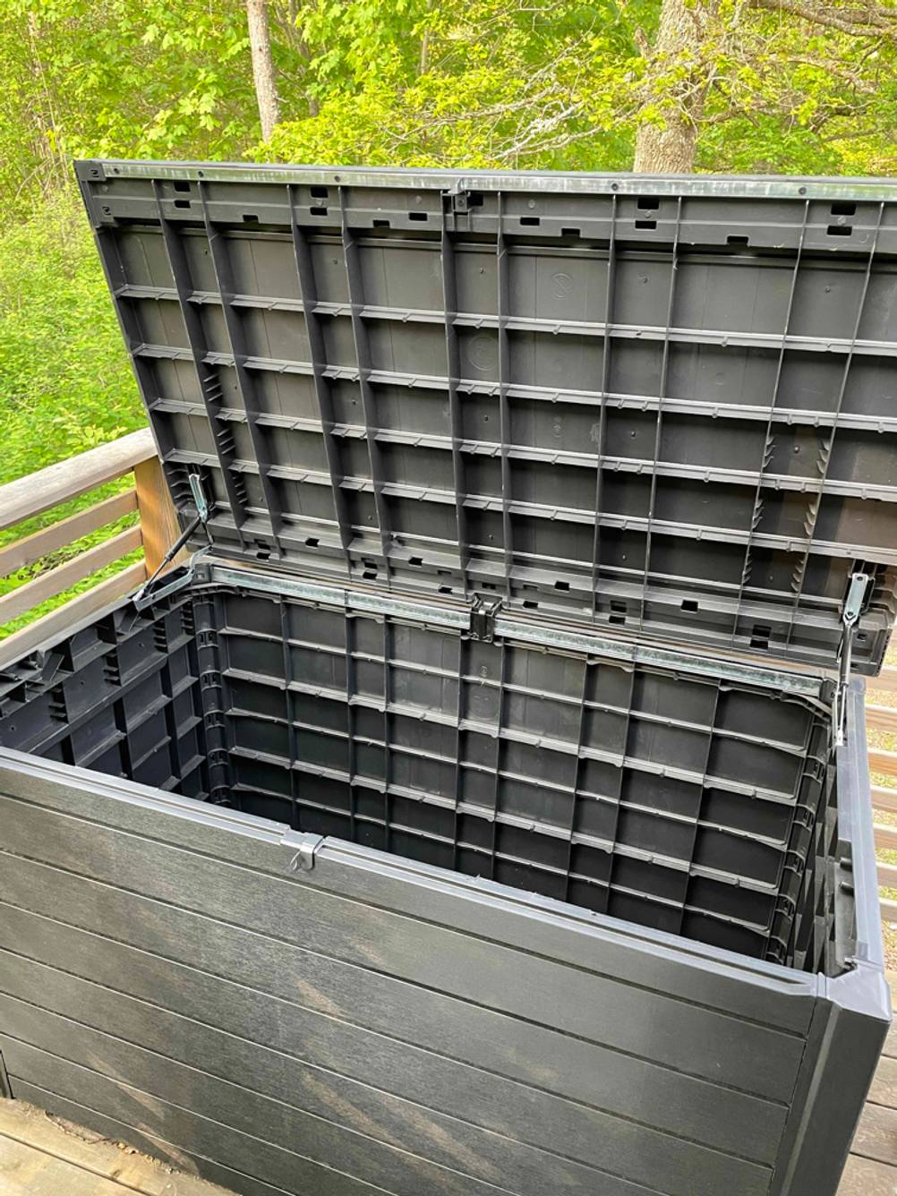 Eine geöffnete Auflagenbox in grau auf einer Terrasse.
