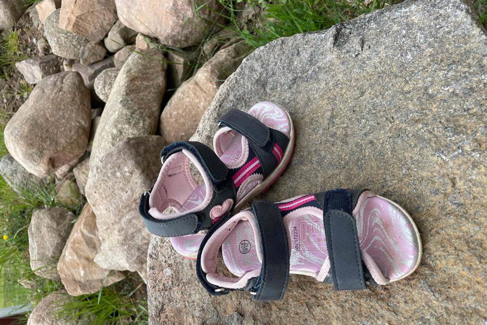 Kindersandalen auf einem großen Stein.