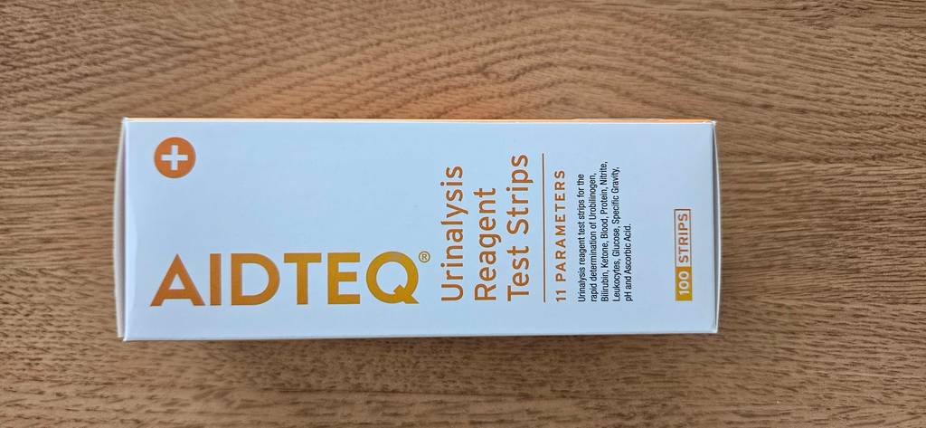 Im Test: Eine Packung mit Urinteststreifen liegt horizontal auf einer Holzfläche.