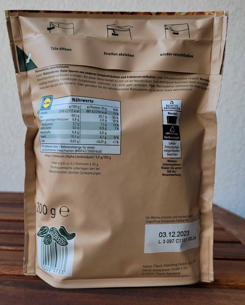 Walnüsse im Test: Verpackungsrückseite von Walnüssen aufrecht stehend auf einem Holztisch.