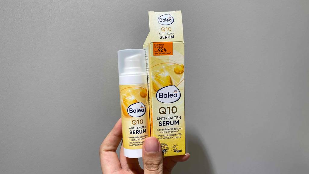 Anti-Falten-Serum im Test: Eine Hand hält eine Tube Serum und deren Verpackung vor grauen Hintergrund