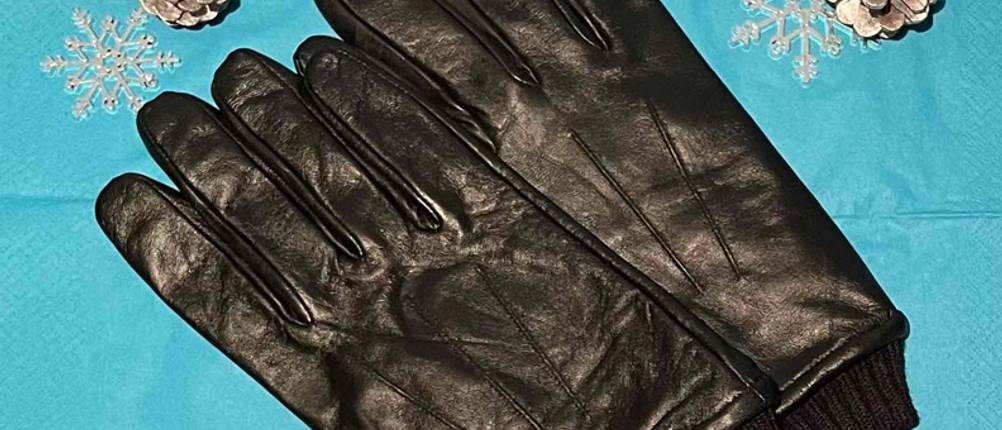 Lederhandschuhe Herren im Test: Zwei Handschuhe nebeneinander mit Dekozapfen auf blauer Serviette