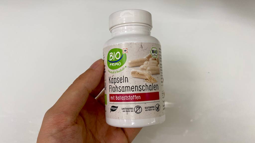 Flohsamenschalen-Kapseln getestet: Eine Hand hält eine Dose vor hellem Hintergrund
