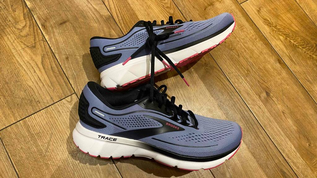 Brooks-Laufschuhe-Test: ein Paar Brooks-Laufschuhe mit Schnürsenkel aneinander gebunden liegen auf einem Holzboden.