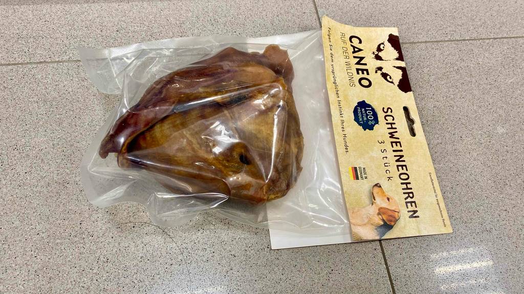 Eine Packung Schweineohren für Hunde im Test auf einem Fliesenboden.
