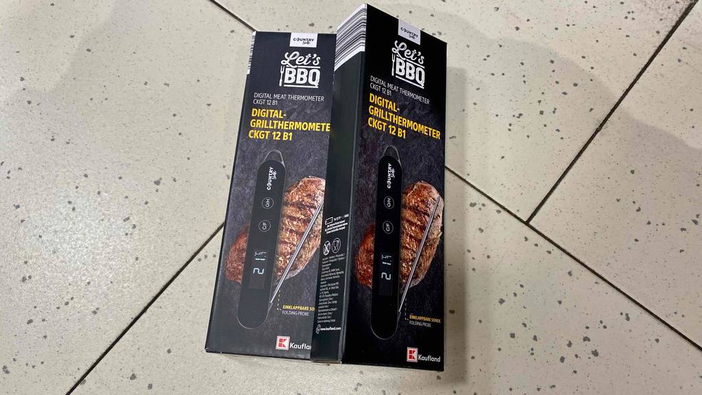 Grillthermometer getestet: Zwei verpackte Grillthermometer liegen leicht übereinander auf einem Steinboden.
