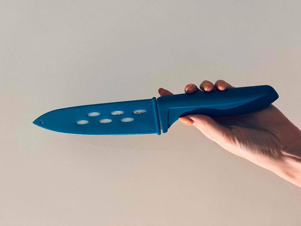 Keramikmesser im Test: Keramikmesser mit blauer Schutzkappe wird in der Hand gehalten.
