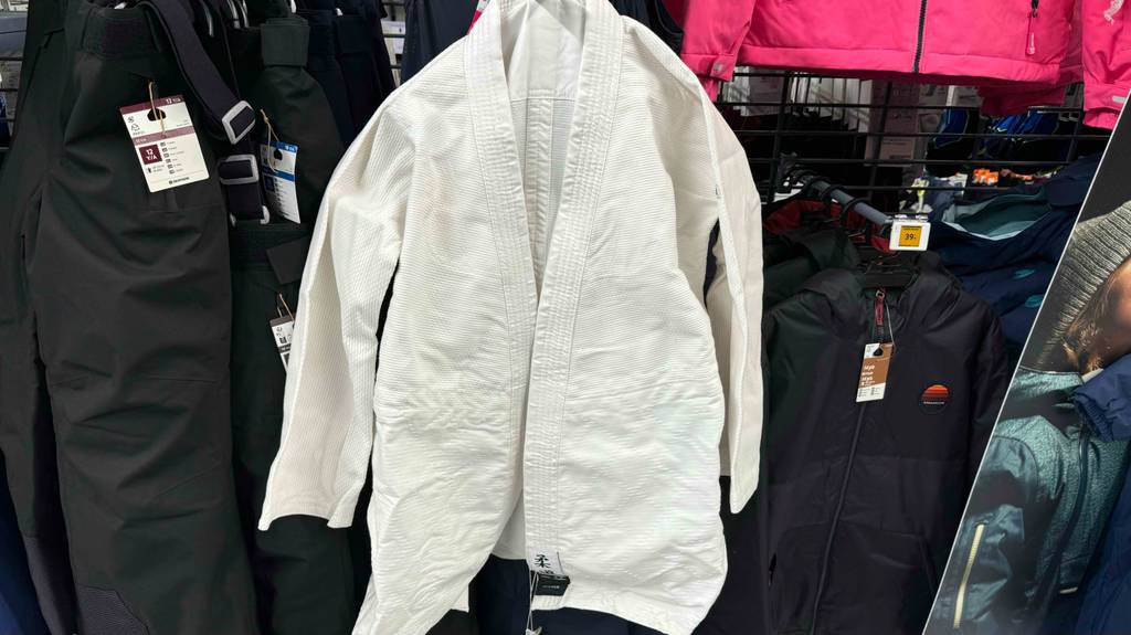 Ein weißer getesteter Judoanzug hängt auf einem Kleiderbügel, der von vorn ersichtlich ist.
