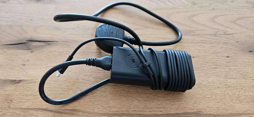 Das Ladekabel eines getesteten Dell-Laptops auf einer Holzoberfläche.