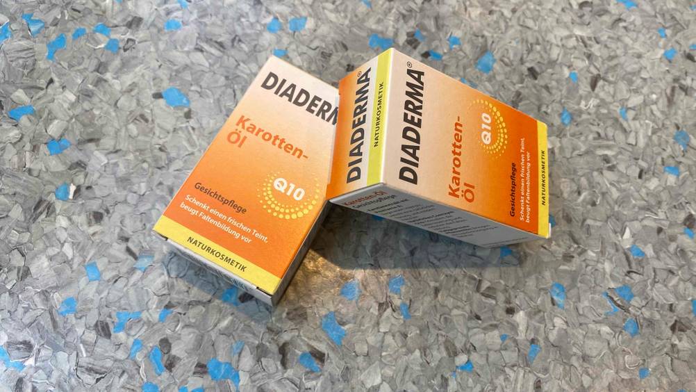 Karottenöl getestet: Zwei Packungen liegen leicht übereinander auf einer grauen Fläche.