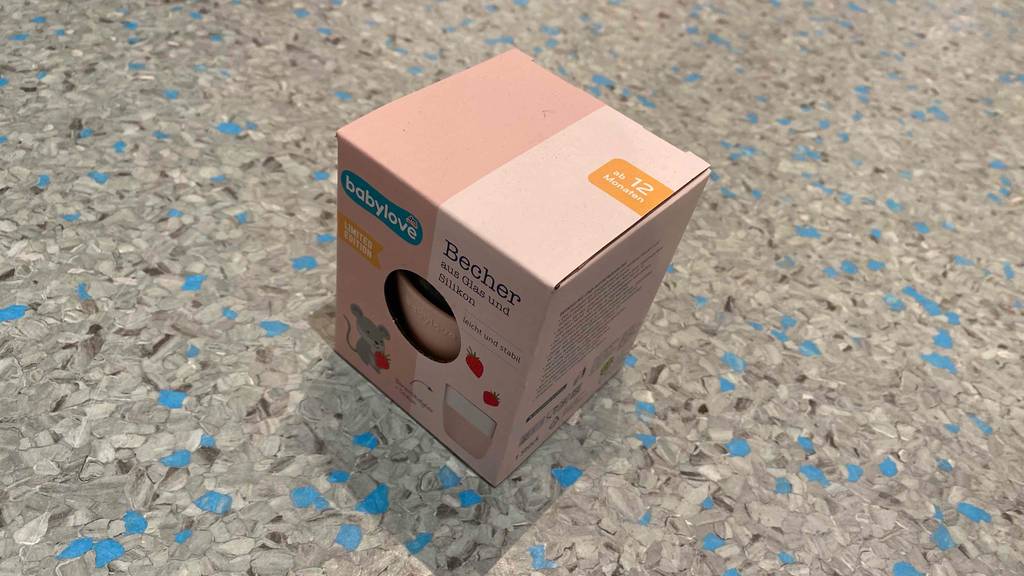 Auf einer grauen Oberfläche steht ein getesteter Trinklernbecher in Originalverpackung.