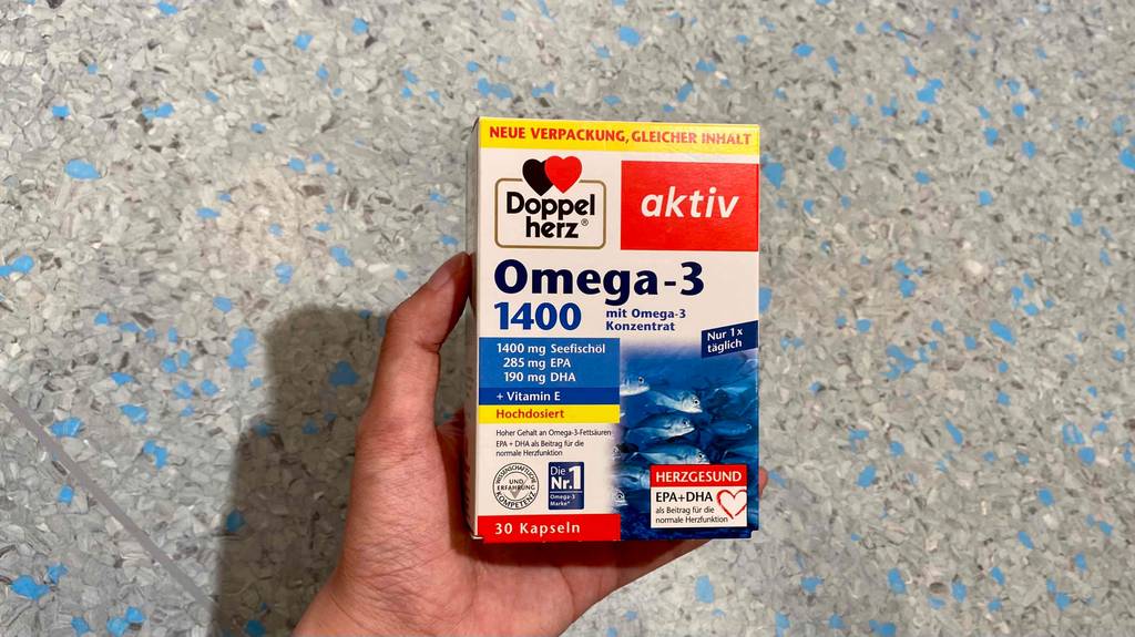 Omega-3-Öl getestet: Eine Hand hält eine Packung vor hellen Hintergrund