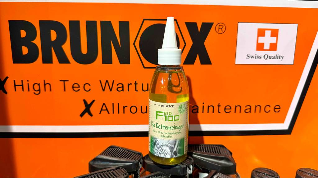 Kettenreiniger getestet: Die Dosierflasche mit dem Bio Kettenreiniger steht vor einem Plakat für Wartungsprodukte im Verkauf.