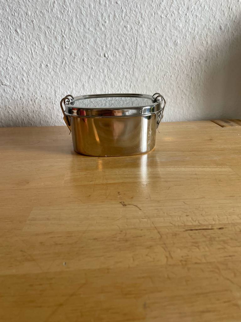 Die geschlossene Brotdose aus Metall im Test steht auf einem Holztisch.