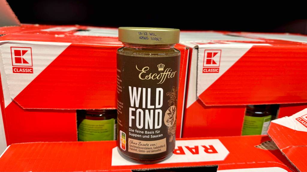 Ein getestetes Glas Wildfond steht vor roten Kartons.