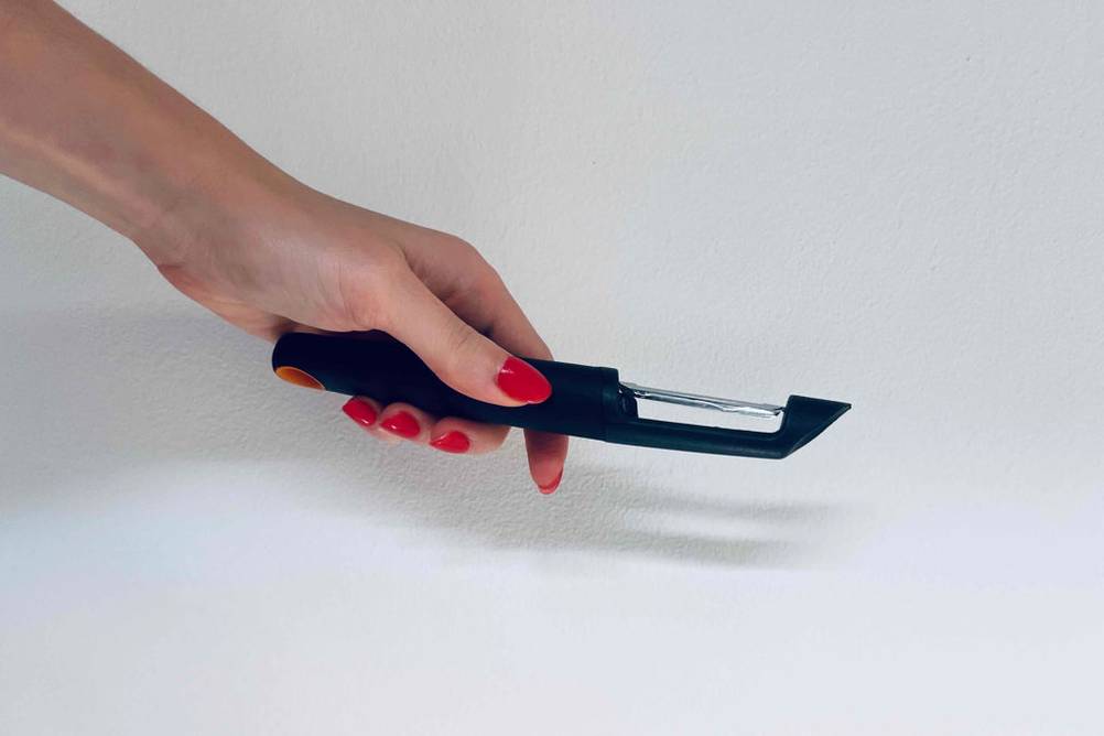Spargelschäler getestet: Eine Hand hält einen Schäler vor eine helle Wand